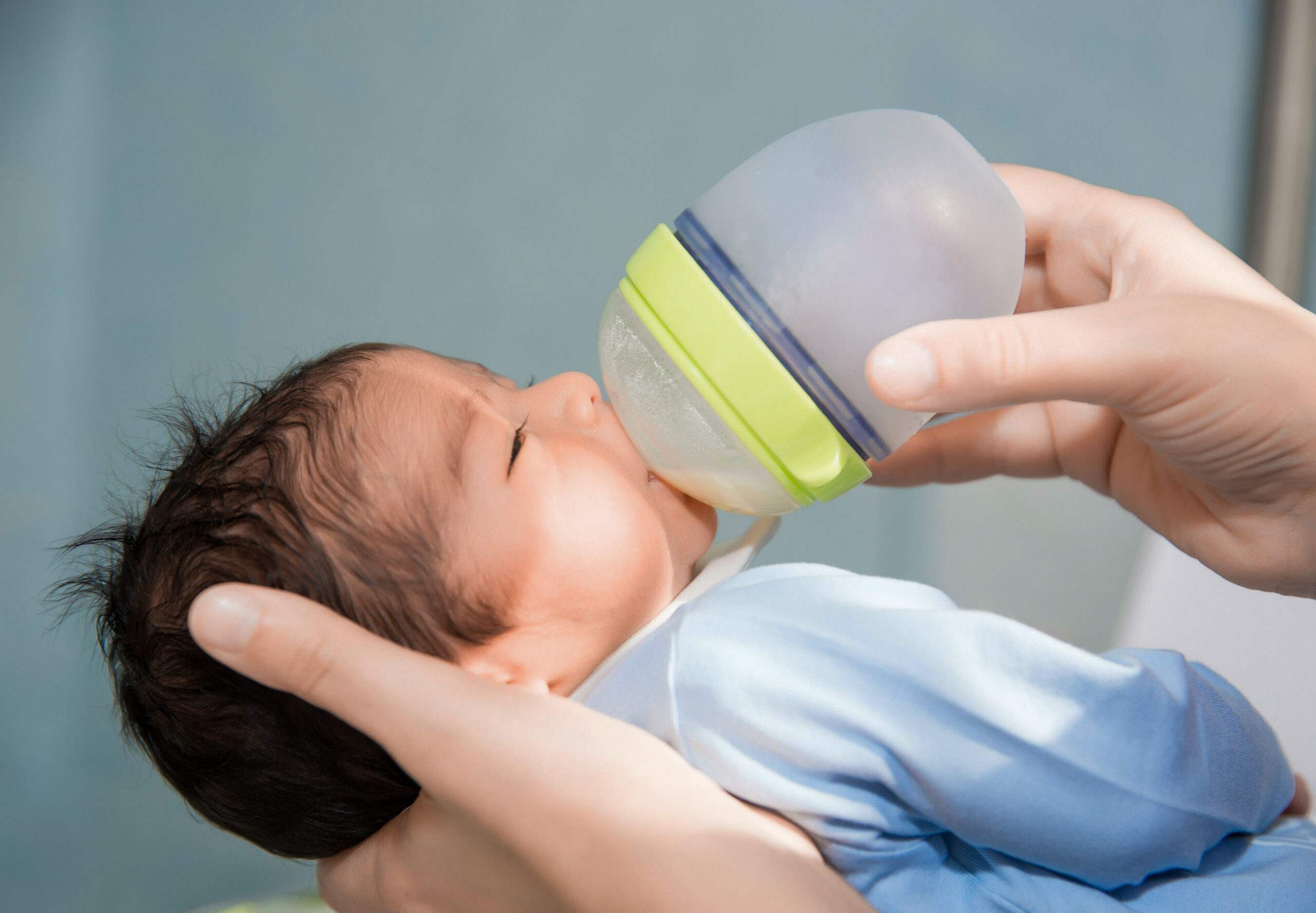 newborn baby is being fed from small bottle at the hospital