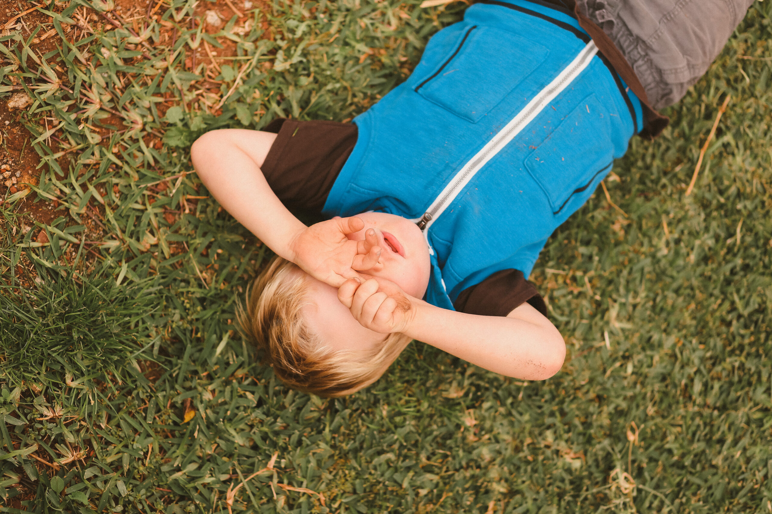 A portrait of a little boy lying in a pretty garden setting